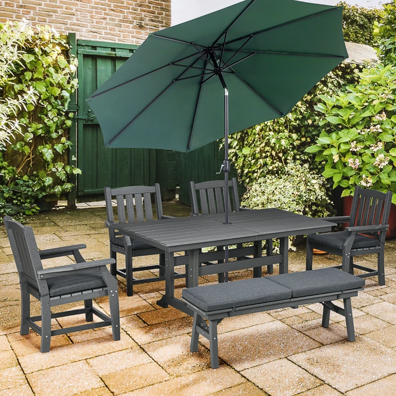 Outdoor patio dining set with green umbrella and cushioned seating on stone patio.