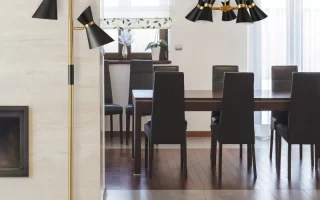 Gold and black floor lamp next to dining table and chairs
