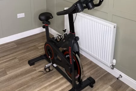 Indoor exercise bike with black frame and red detailing in modern home gym