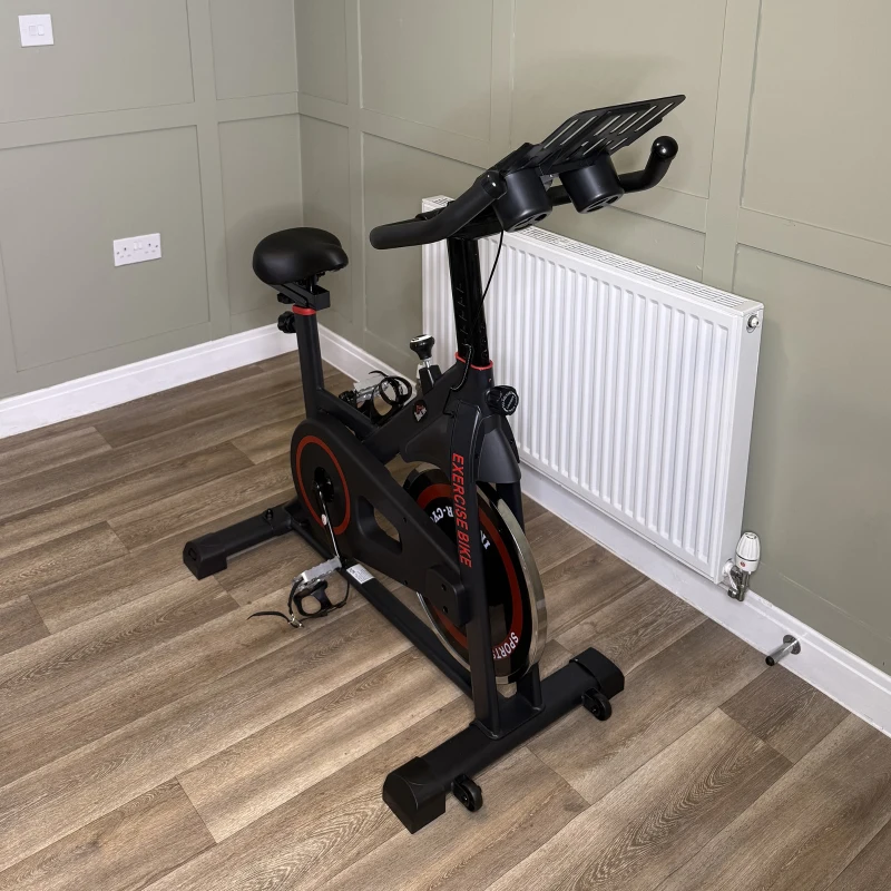 Indoor exercise bike with black frame and red detailing in modern home gym
