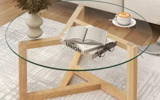 Glass coffee table with wooden star-base holding coffee and books.