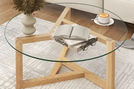 Glass coffee table with wooden star-base holding coffee and books.