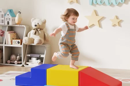 Toddler climbing colorful foam blocks in bright playroom