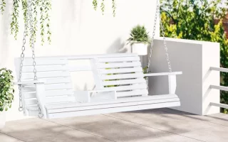 White hanging porch swing on patio with greenery above.
