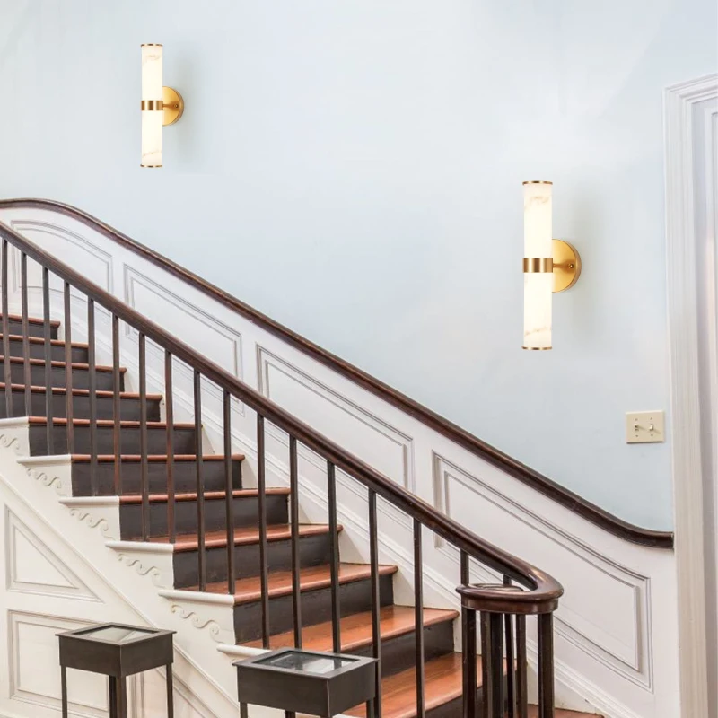 Staircase with two gold wall sconces illuminating white walls