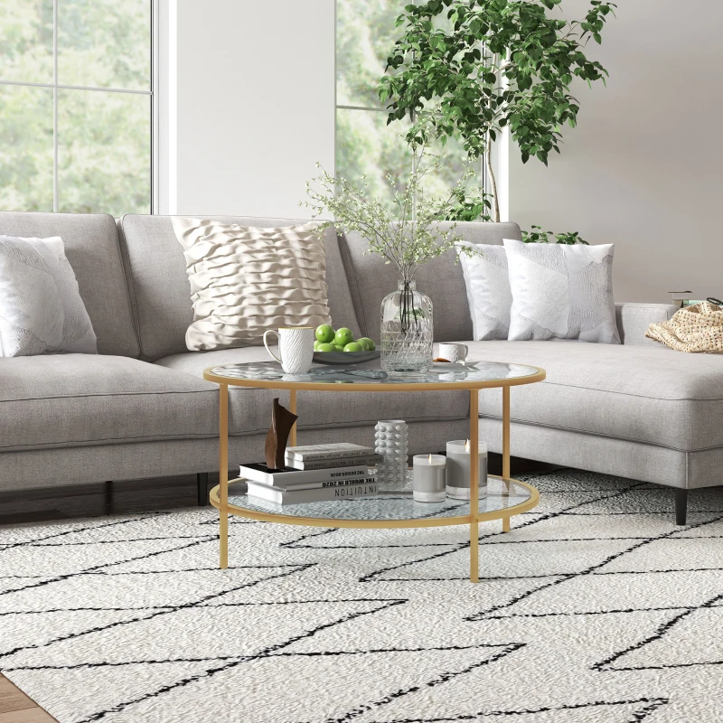 Glass round coffee table with gold metal frame beside grey sectional sofa.