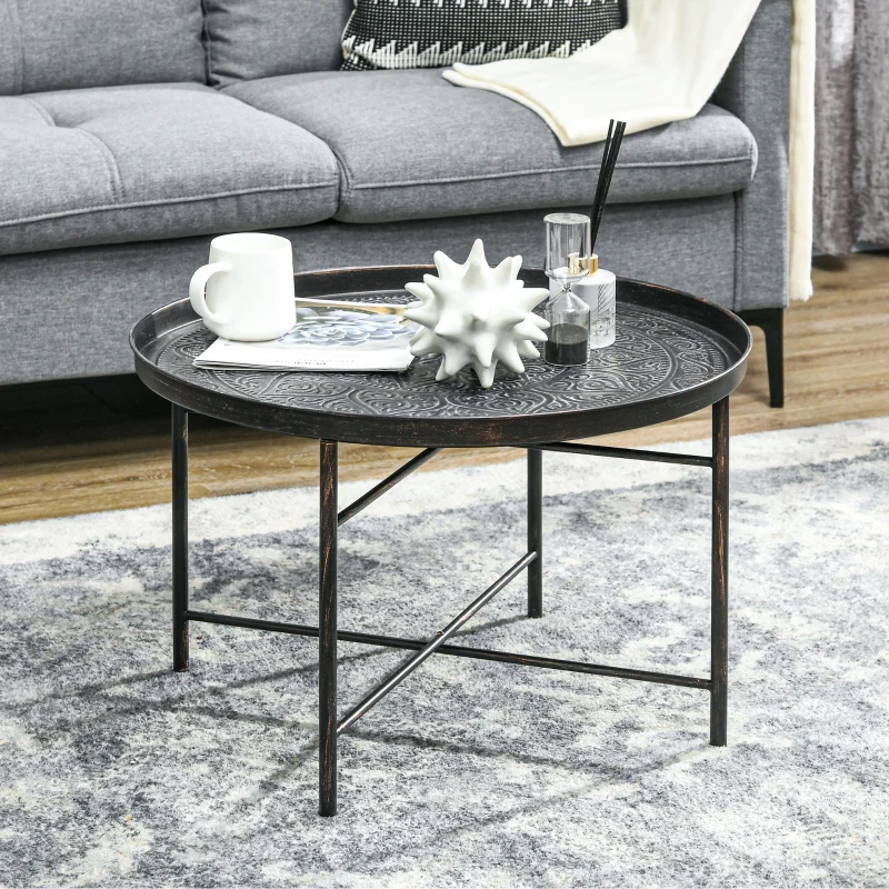Black metal round coffee table with decorative tray top beside grey sofa.