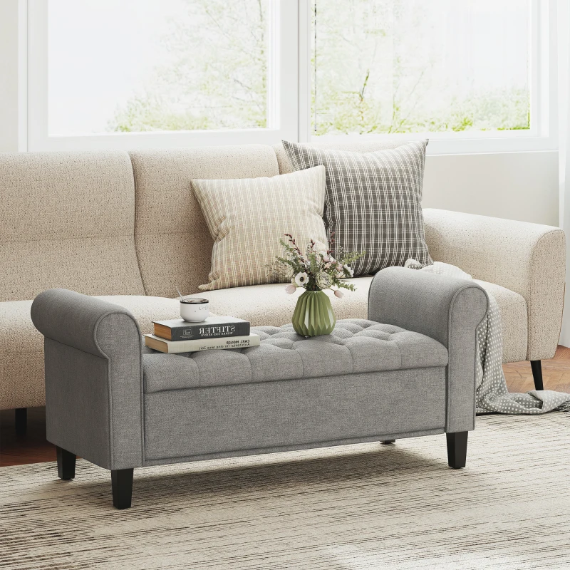 Gray tufted storage ottoman bench with rolled arms in living room