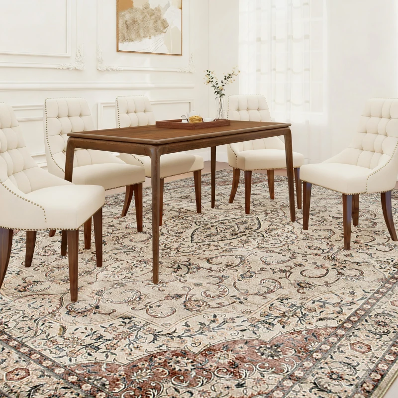 Elegant dining room with wooden table, white chairs, and ornate floral rug.