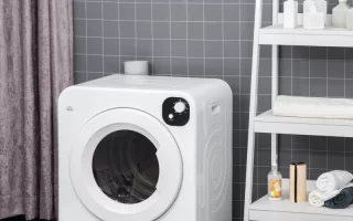 Compact white HOMCOM laundry dryer placed beside shelf in tiled laundry room