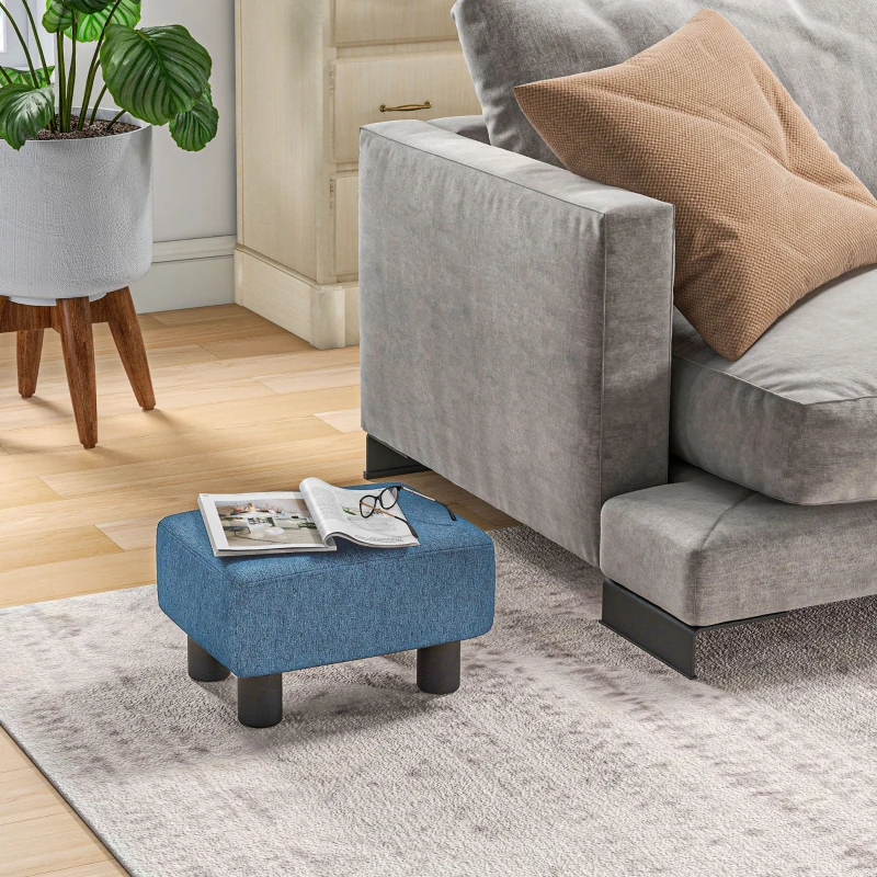 Small blue cube ottoman beside gray sofa with magazine.
