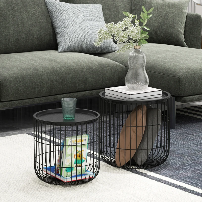 Black wire frame nesting side tables with books and vases near green sofa.