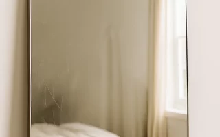Lightly scratched mirror reflecting a bedroom before the scratch removal process.