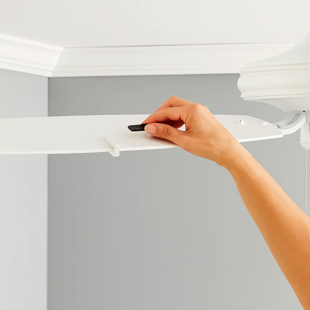 Hand placing balancing weight on ceiling fan blade to reduce wobble and vibration.
