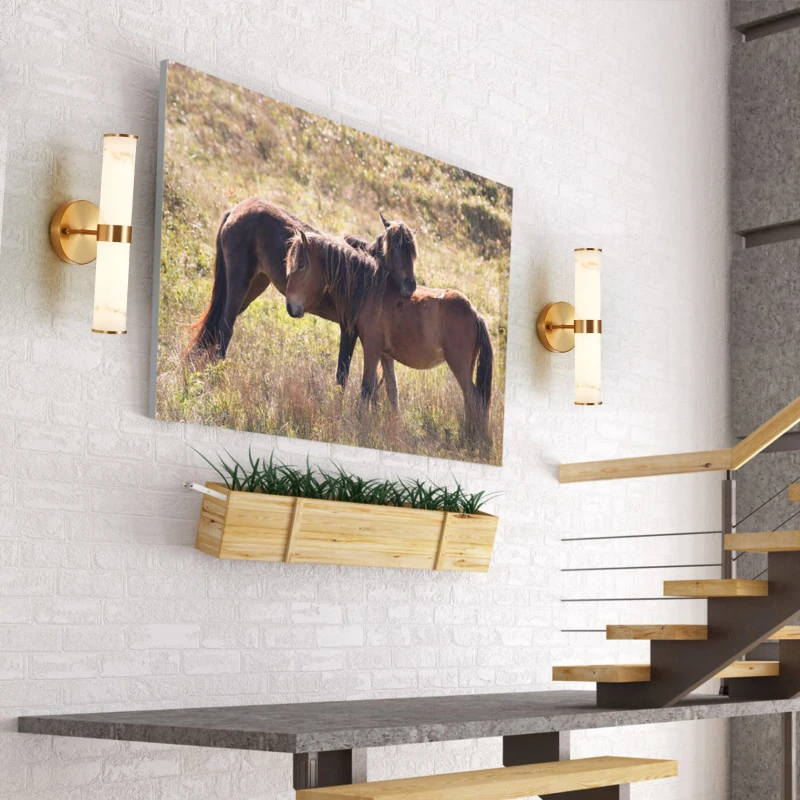 Wall lights with gold finish highlighting artwork in bright hallway