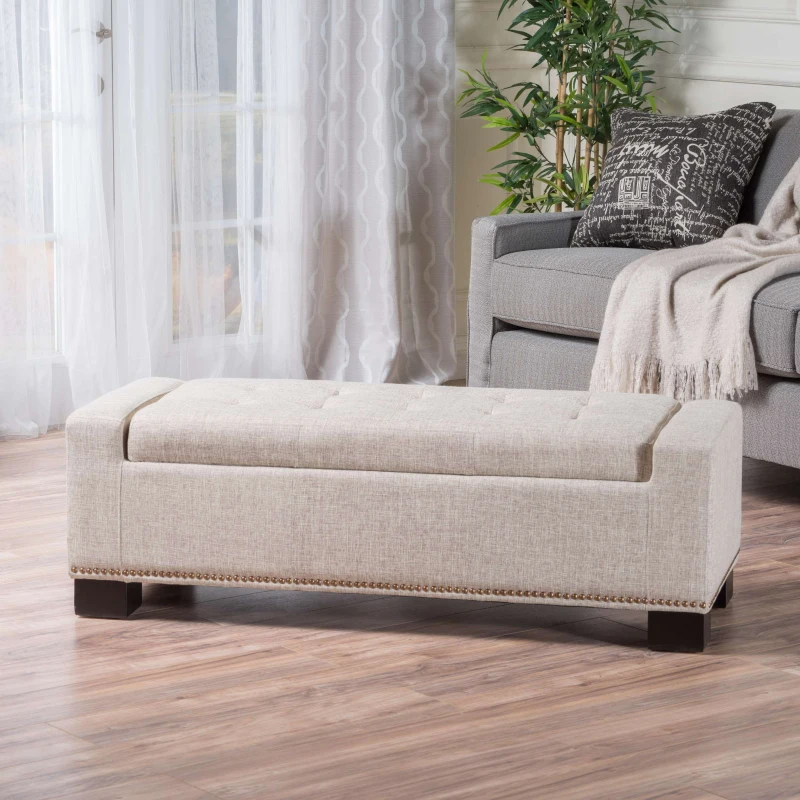 Beige fabric storage ottoman in bright living room with sofa
