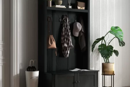 Modern black hall tree with coats, hats, and plants in entryway.