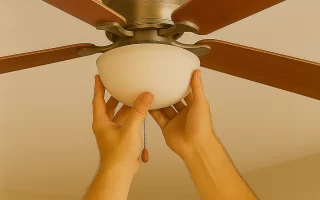 Hands tightening light fixture onto ceiling fan with wooden blades