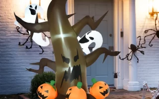 Inflatable Halloween tree with glowing pumpkins and ghosts outdoors.