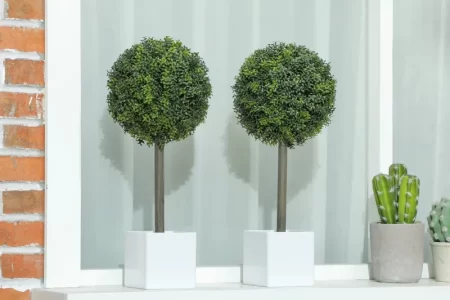 Two finished artificial topiary balls placed on white window ledge.