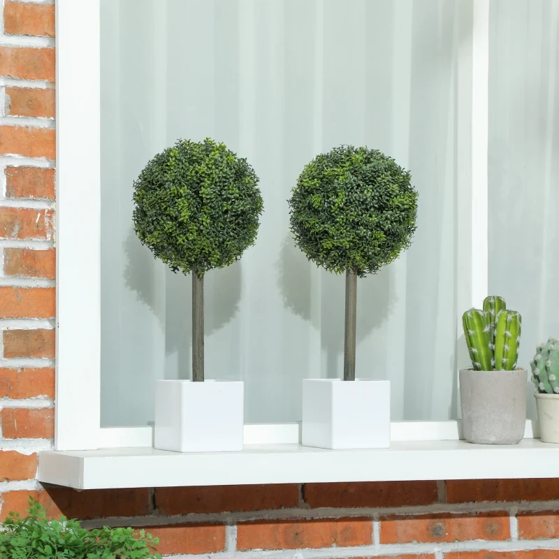 Two finished artificial topiary balls placed on white window ledge.