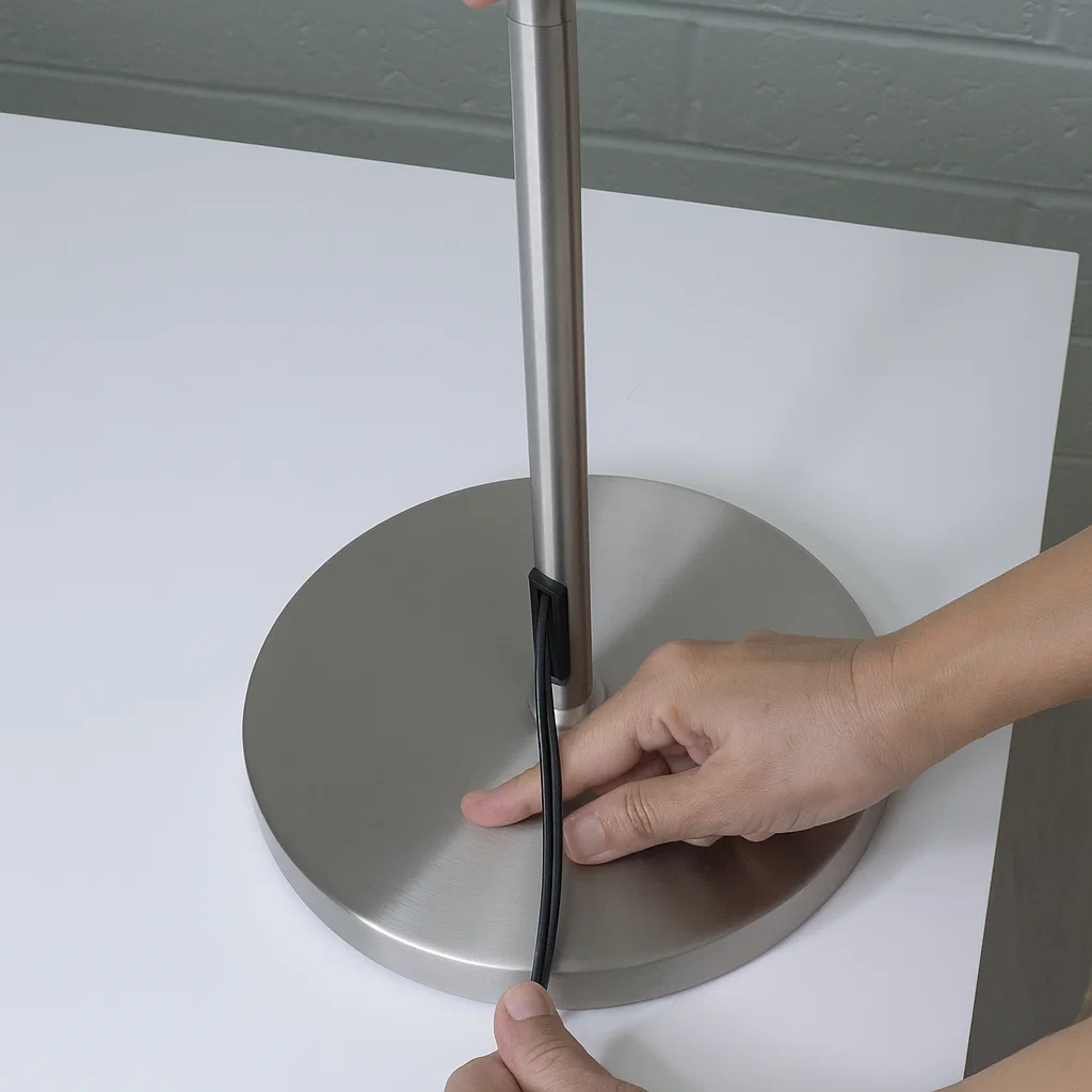Hands arranging lamp cord neatly through base opening