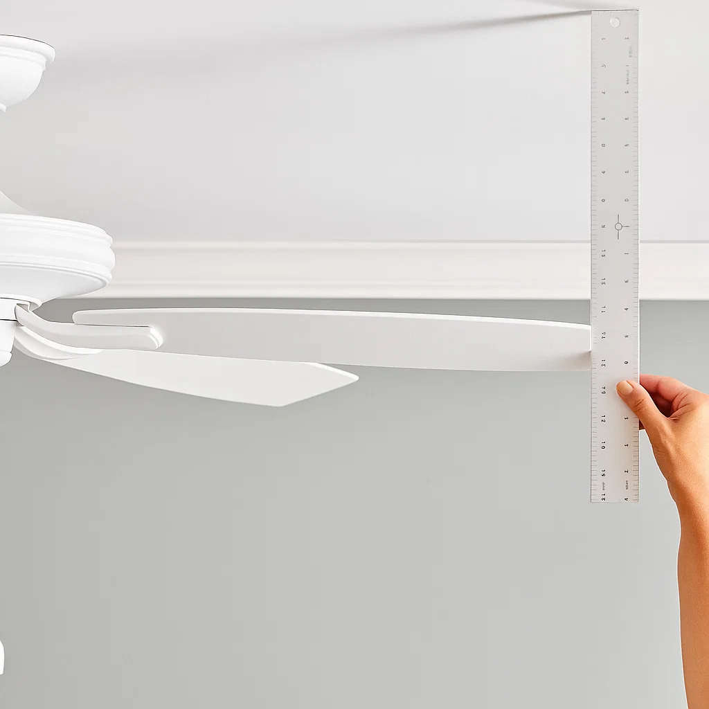 Measuring tape checking ceiling fan blade height for alignment and even balance.
