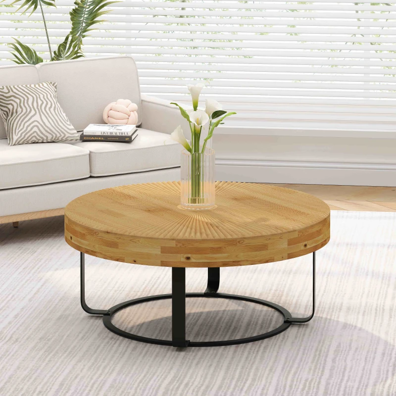 Round wooden coffee table with black metal base in bright living room.