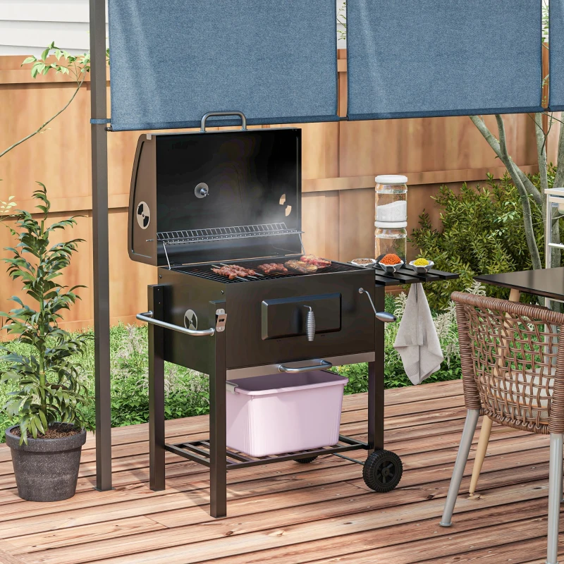 Black outdoor charcoal grill smoking meat beside garden table.