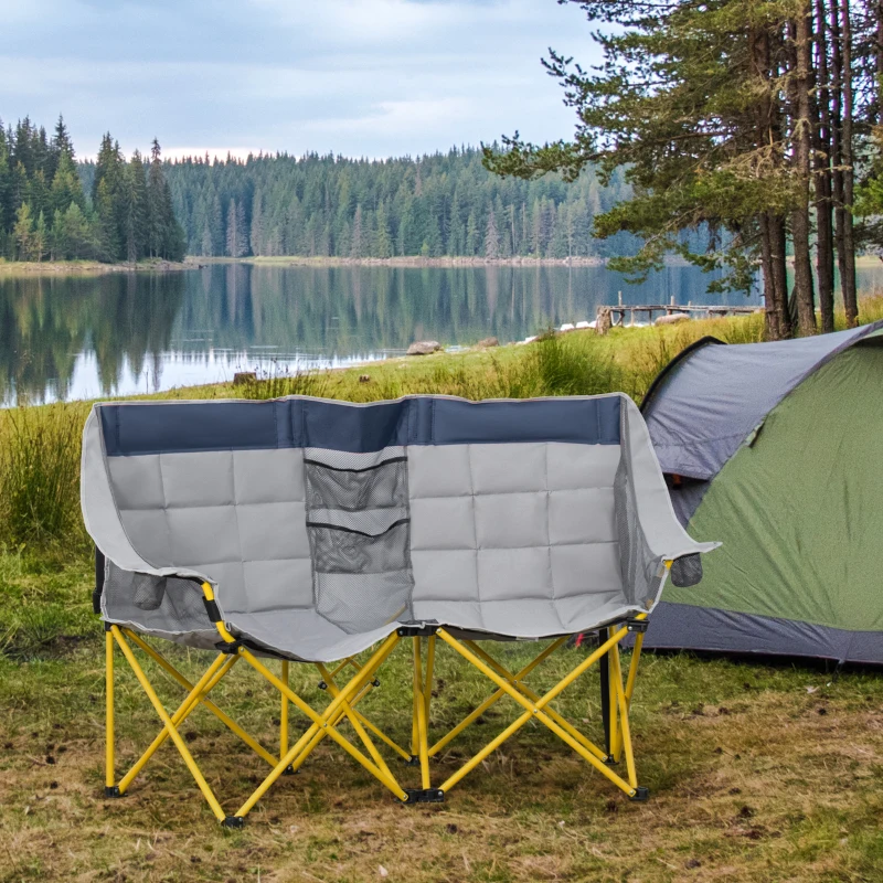 Double camping chair with padded seats beside tent near lake