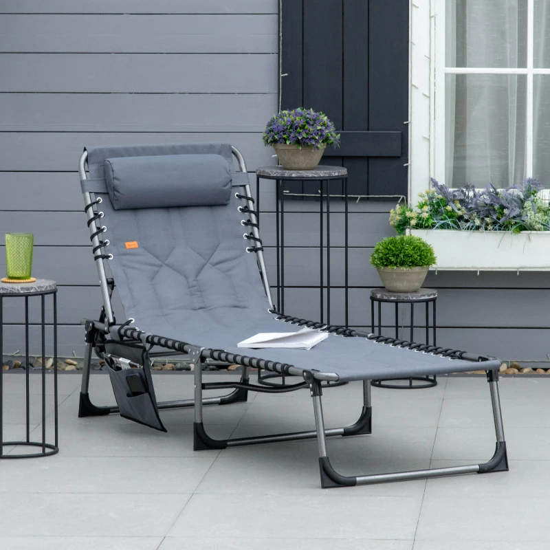 Grey padded folding lounger on patio with side tables and plants