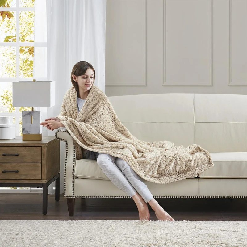 Woman relaxing on a sofa wrapped in a soft beige faux fur throw.