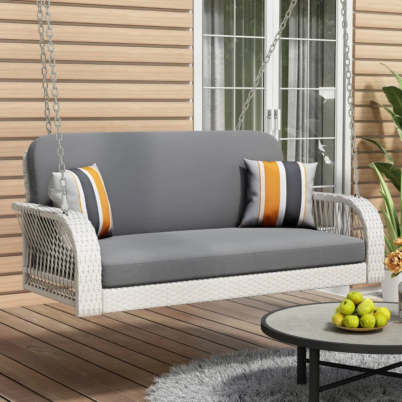 White wicker porch swing with gray cushions and striped pillows.