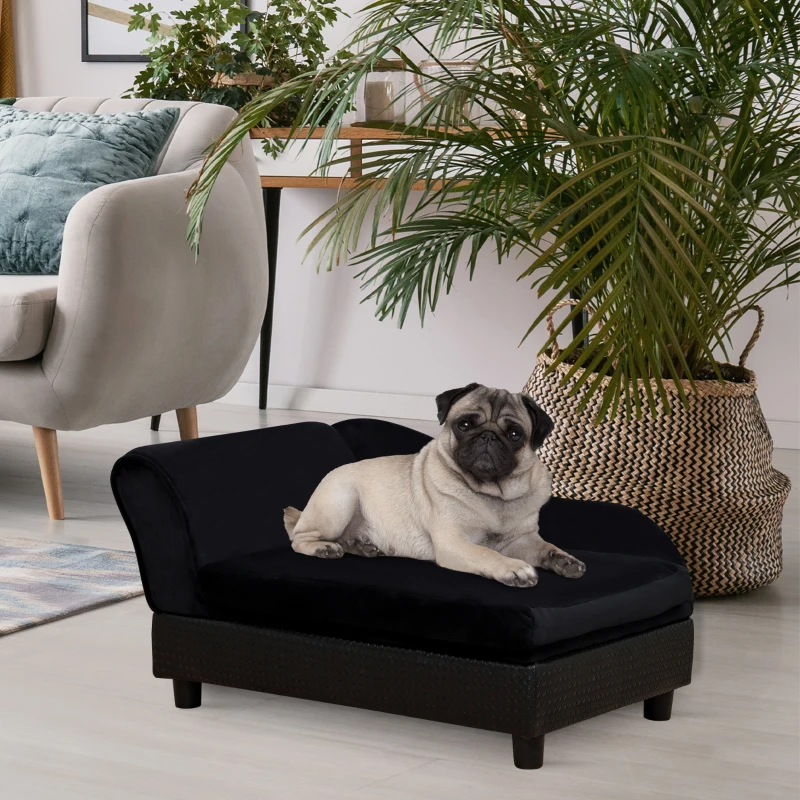 Pug lying on black velvet dog sofa bed indoors
