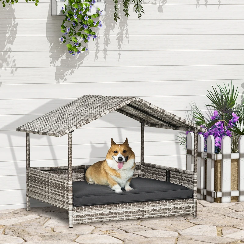 Corgi sitting on gray wicker dog bed with canopy outdoors
