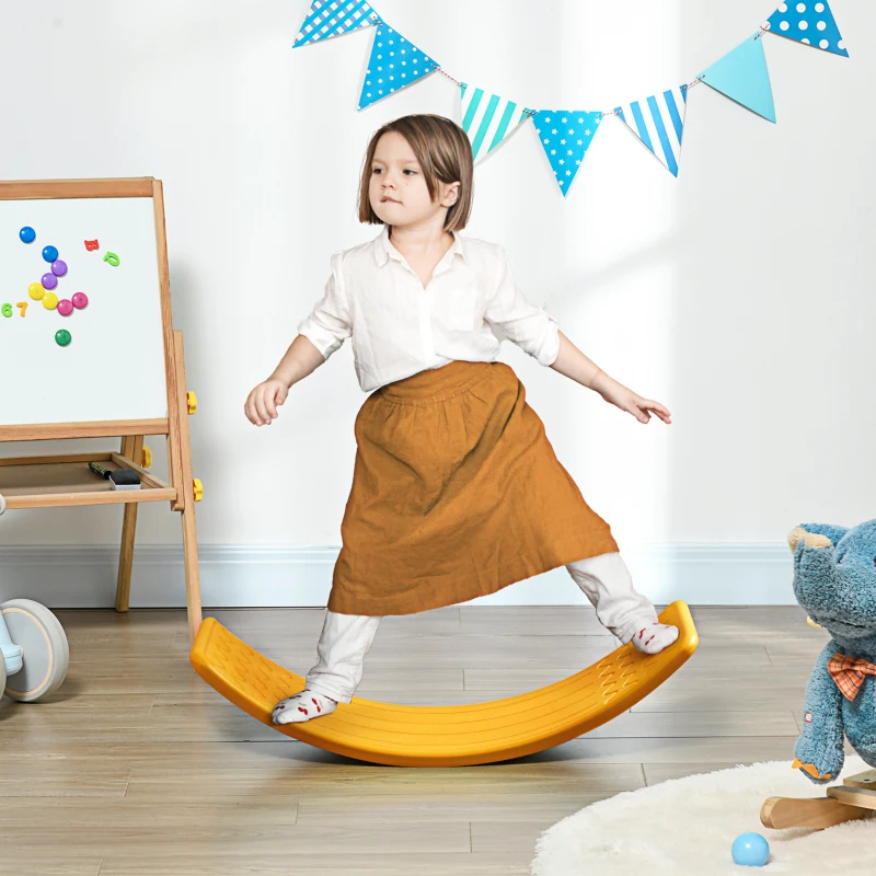 Child balancing on yellow curved wobble board indoors