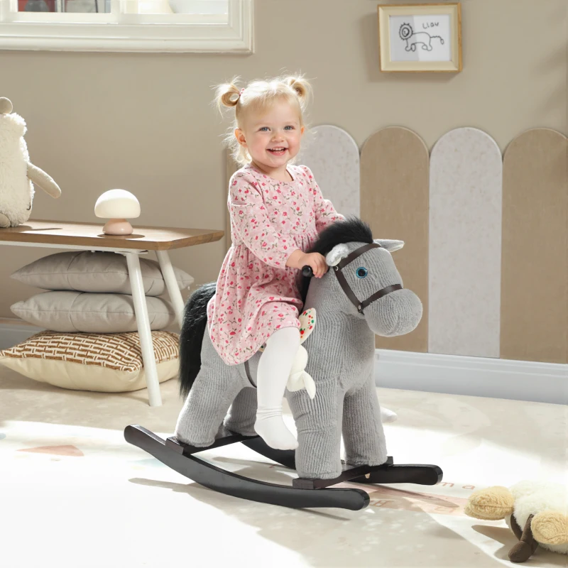 Smiling toddler riding soft gray rocking horse indoors
