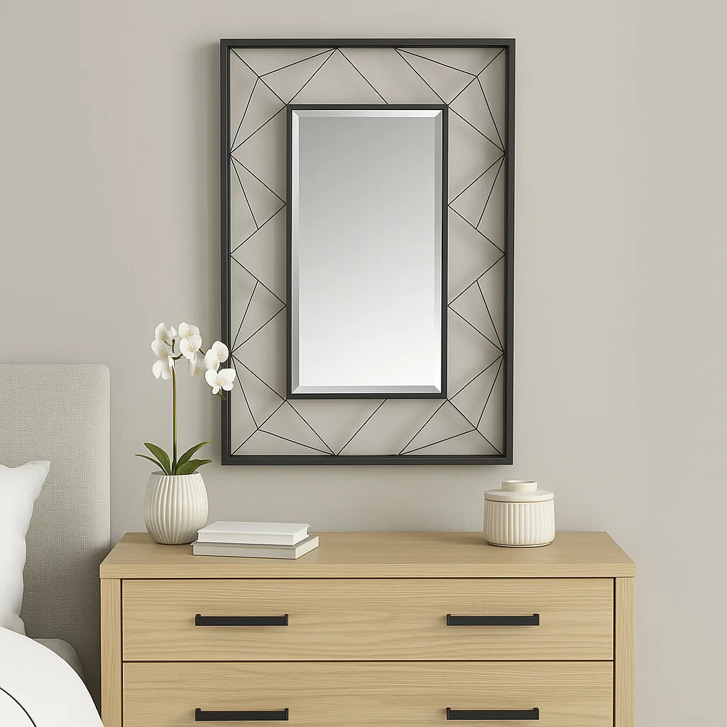 Rectangular mirror with black geometric frame above dresser.