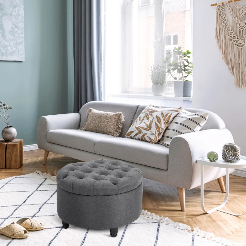 Gray round tufted ottoman in cozy living room near sofa.
