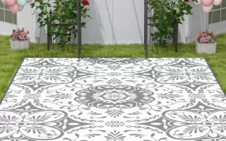 Outdoor setup with white and gray floral rug on grass, surrounded by balloon decorations and garden flowers.