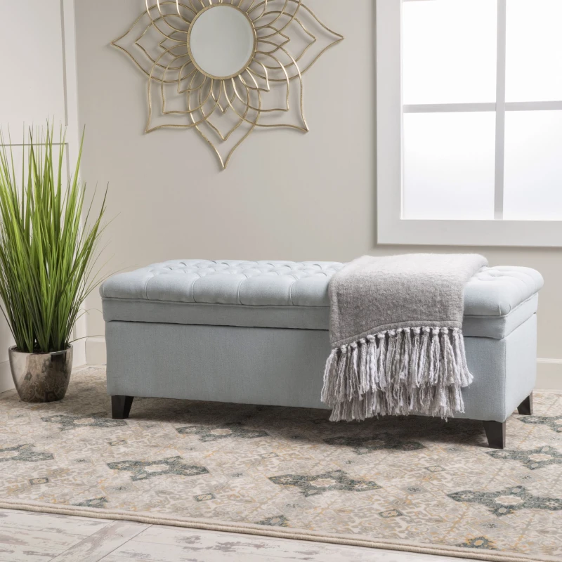 Light blue tufted ottoman bench with throw blanket on top
