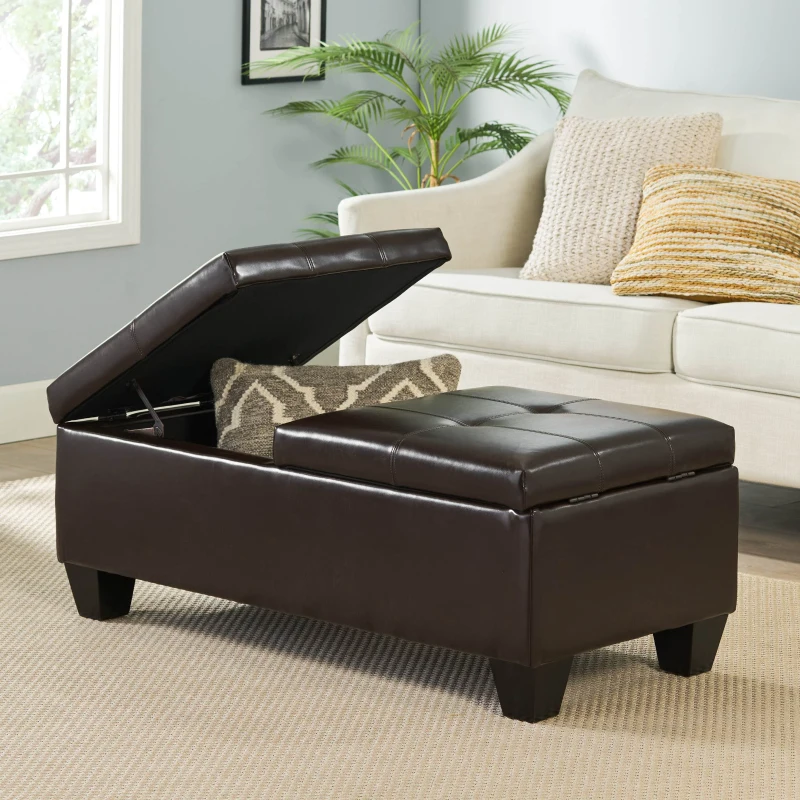 Brown faux leather ottoman with lift-top storage holding pillows.
