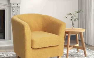 Vintage yellow tufted armchair with nailhead trim in cozy living room.