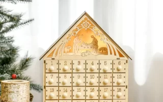 Wooden nativity advent calendar on table with pinecones and berries.