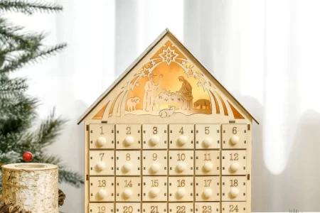 Wooden nativity advent calendar on table with pinecones and berries.