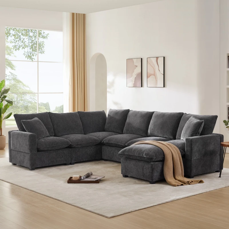 Large dark grey U-shaped sectional sofa with blanket and cushions in bright room.