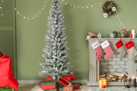 Festive living room with snow-flocked Christmas tree and gifts.