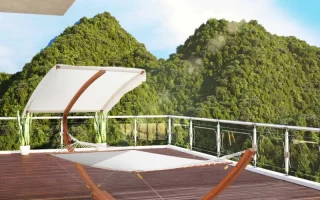 White canopy hammock on wooden stand overlooking green mountains.