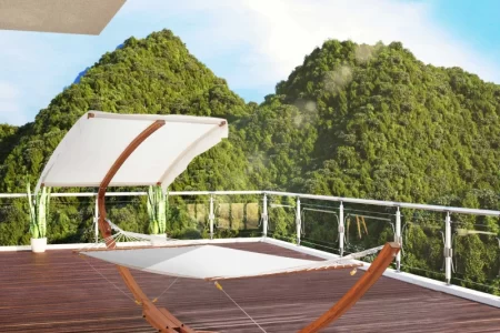 White canopy hammock on wooden stand overlooking green mountains.