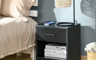 Modern black nightstand beside bed with lamp and books.